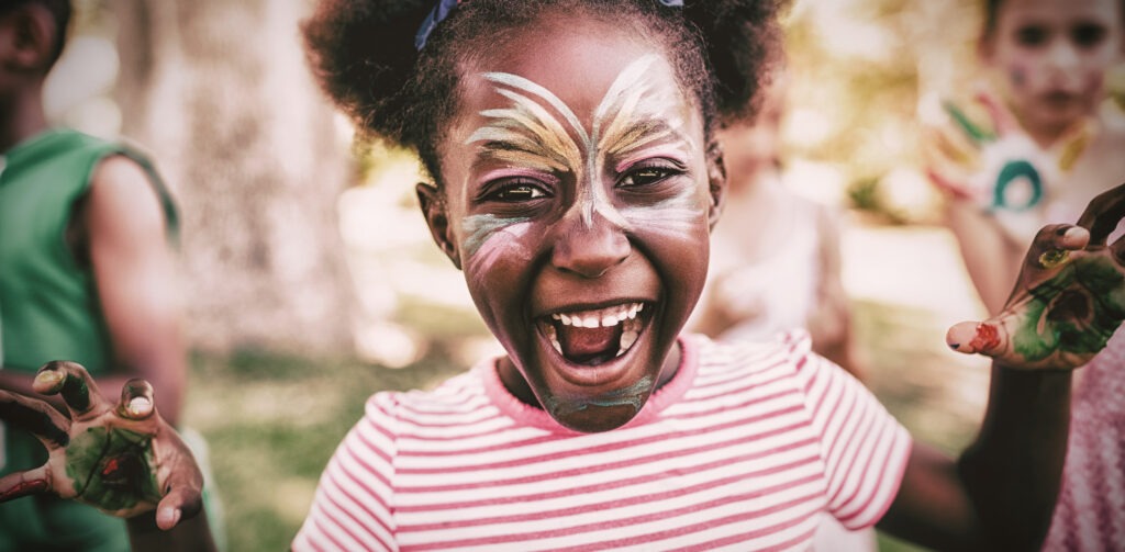 portrait of a girl with make up showing her painted hands in a park